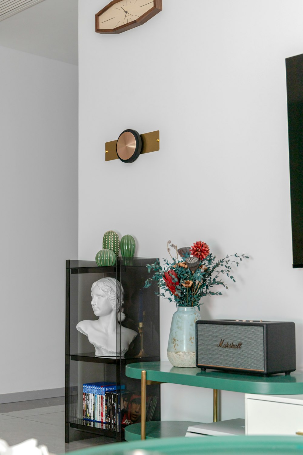 a living room with a vase of flowers and a clock on the wall