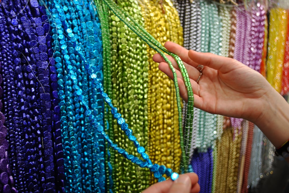 a woman holding a string of beads in front of a wall of beads