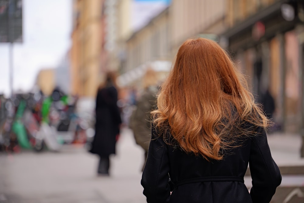 a woman with red hair walking down a street