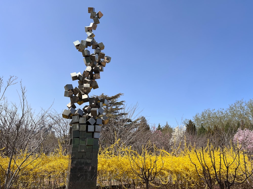 a sculpture in the middle of a field of yellow flowers