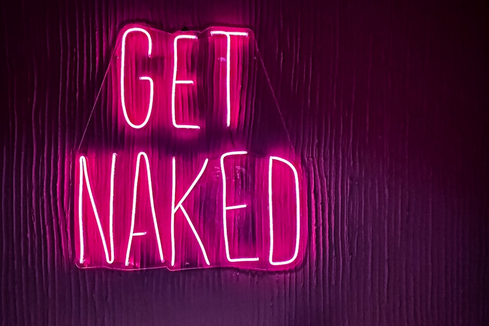 a neon sign that says get naked on a wall