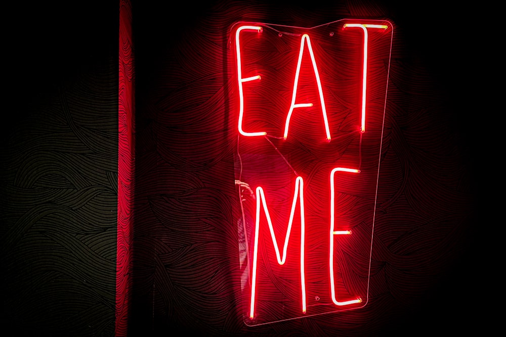 a red neon sign that says eat me