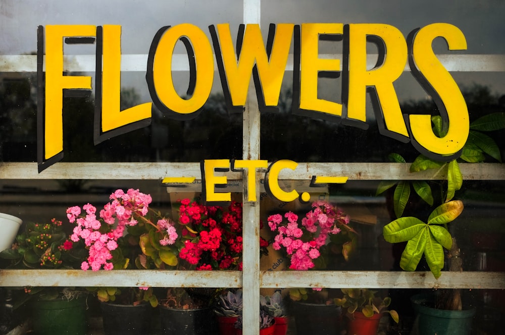 a sign that says flowers etc on the side of a window