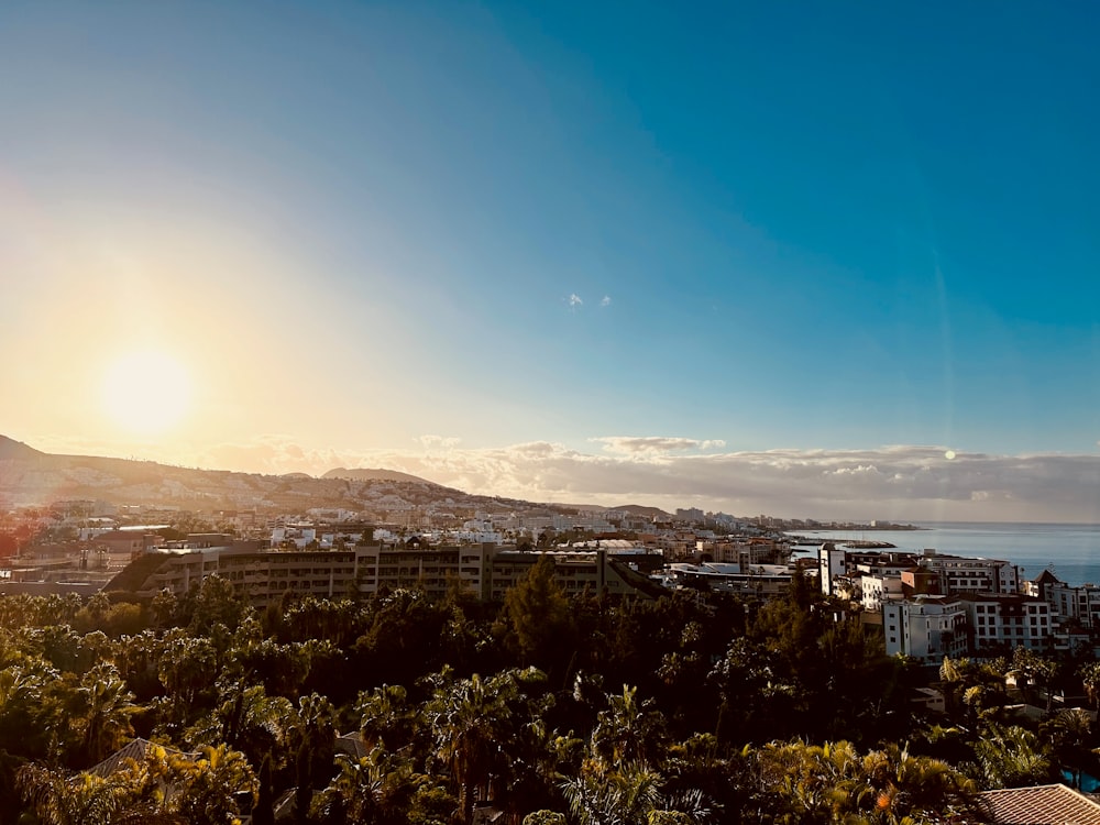 the sun is setting over a city with palm trees