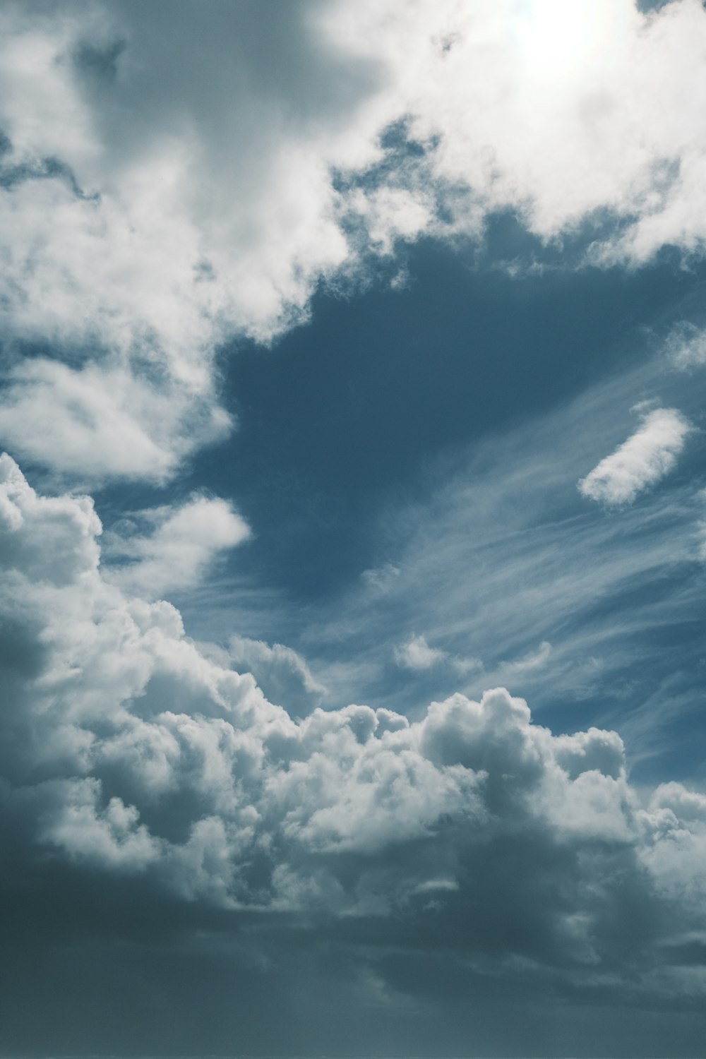 a plane flying through a cloudy blue sky