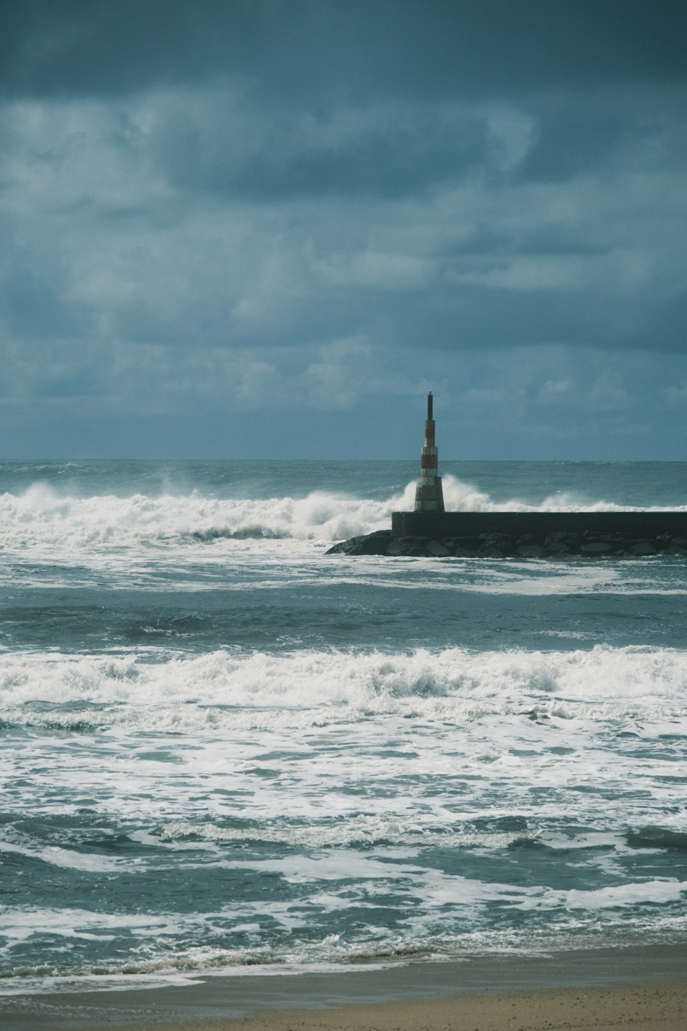 a lighthouse on a rock in the middle of the ocean