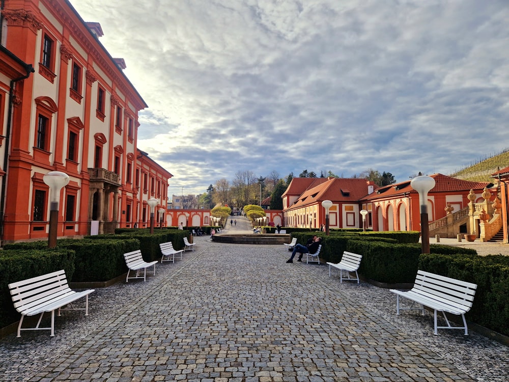 a couple of white benches sitting on top of a cobblestone road