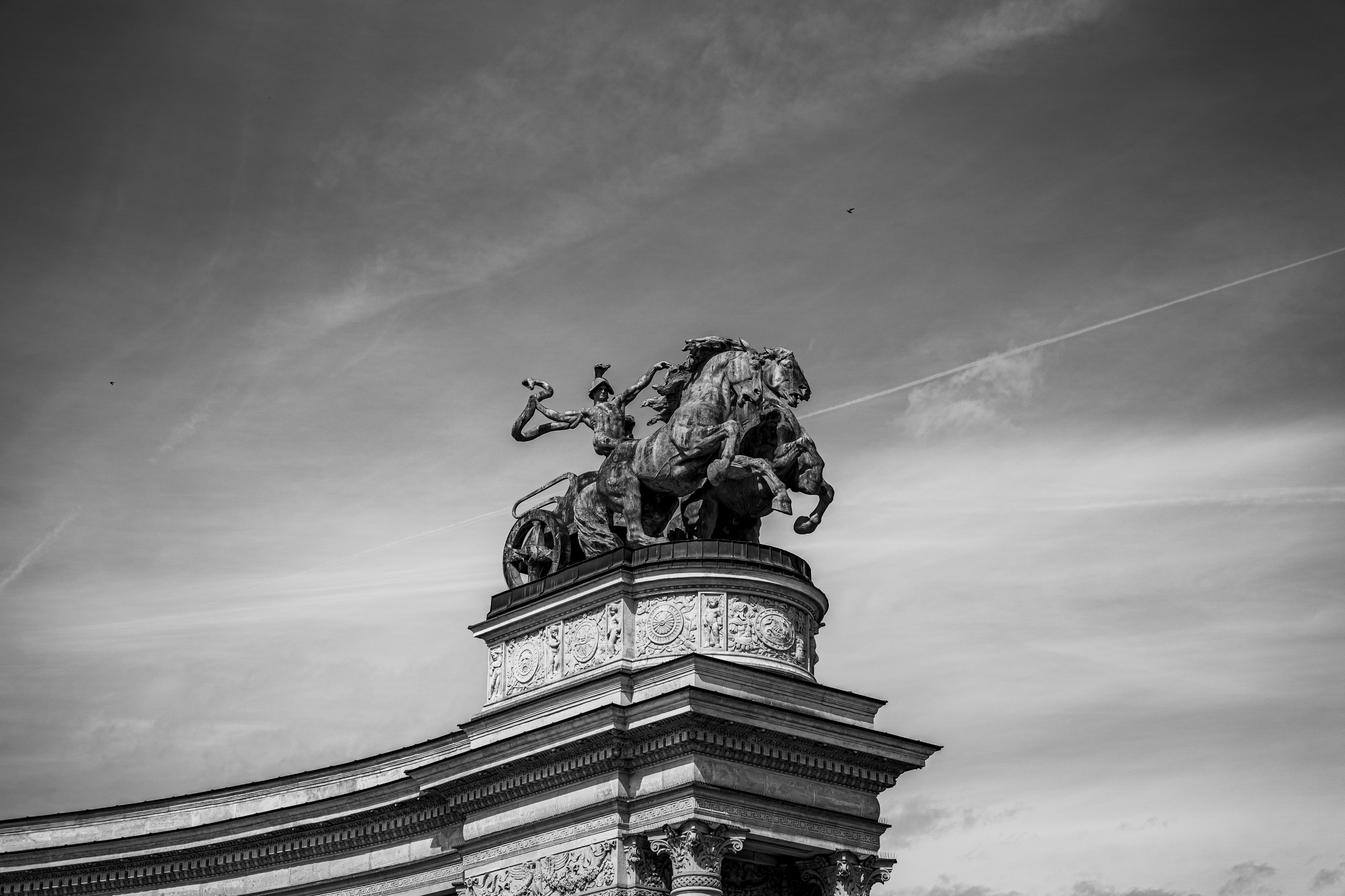 a black and white photo of a statue on top of a building