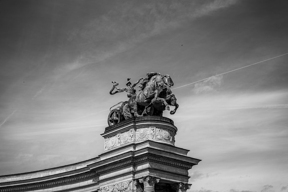 a black and white photo of a statue on top of a building