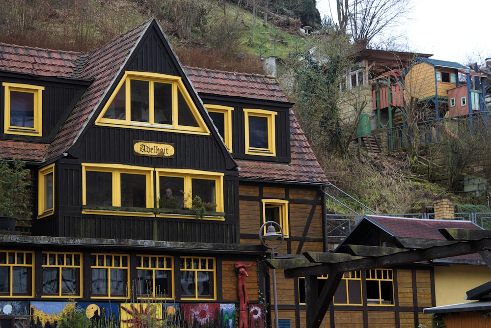 una casa negra y amarilla con una montaña al fondo