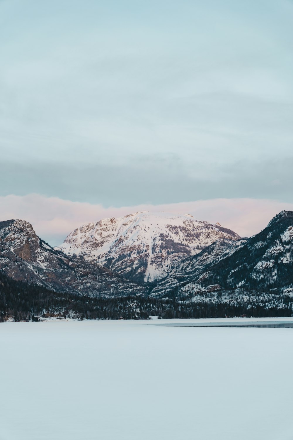 a snow covered mountain range with a lake in the foreground