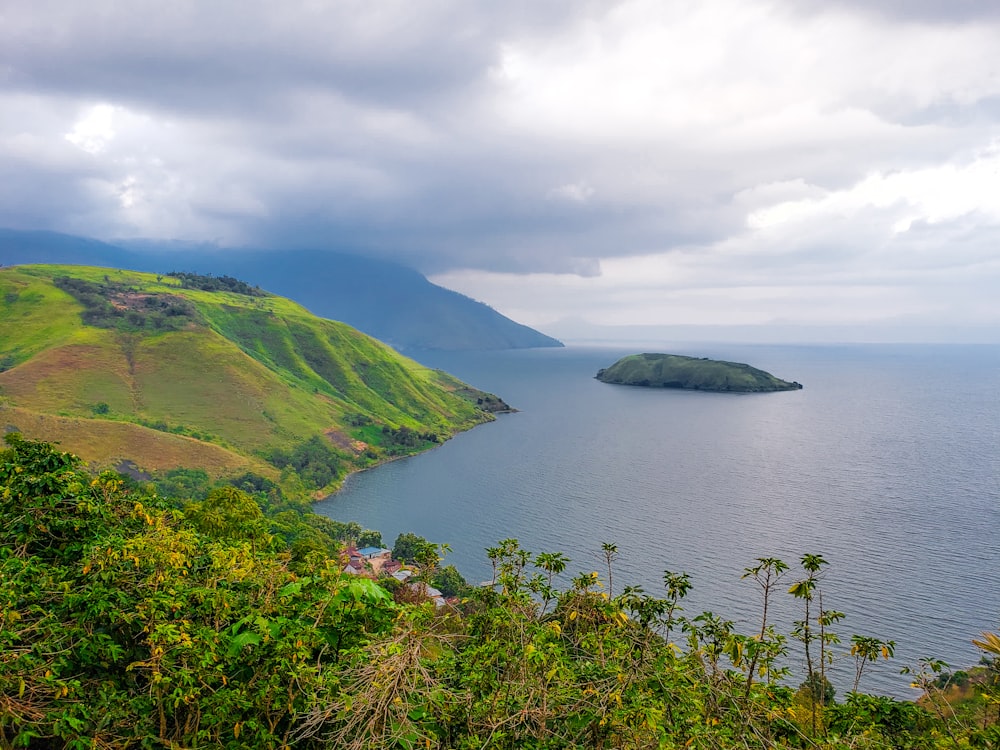 a large body of water surrounded by a lush green hillside