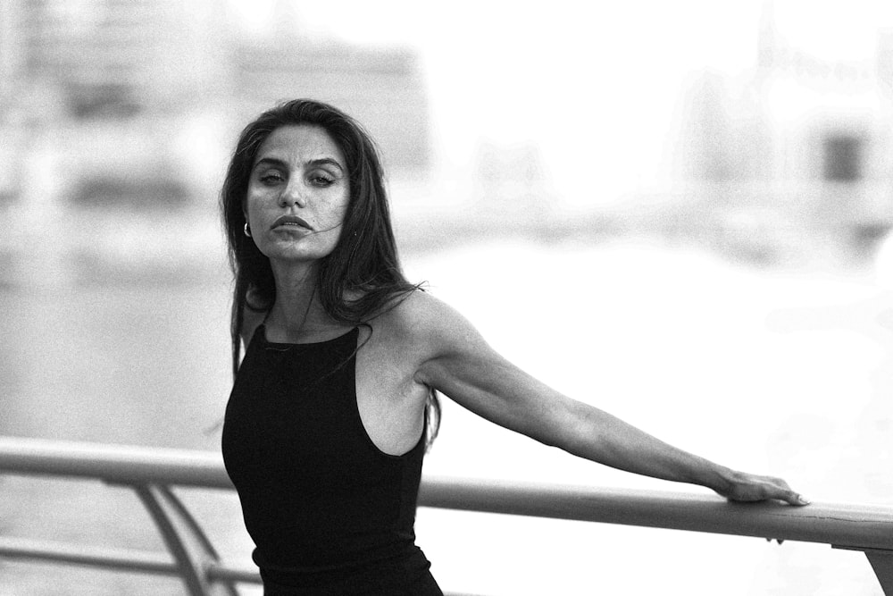 a black and white photo of a woman leaning on a rail