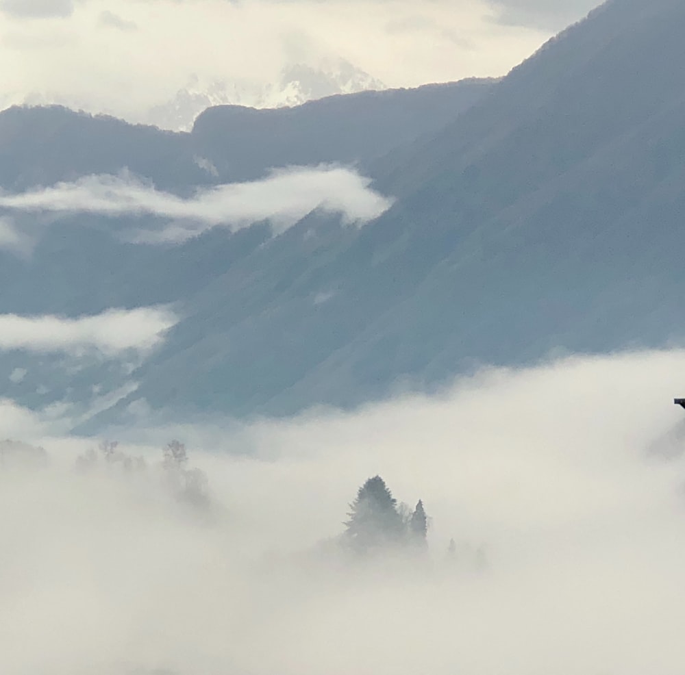 a plane flying through the clouds in the mountains