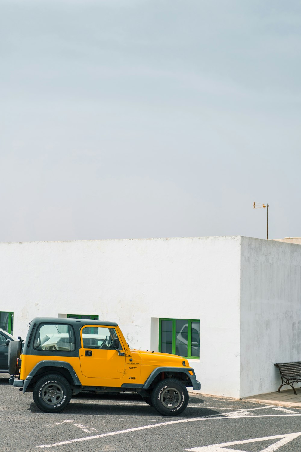 a yellow jeep parked in front of a white building