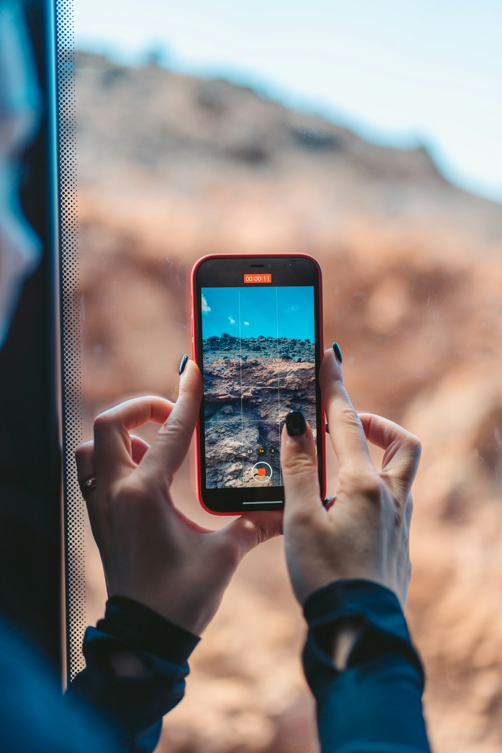 a person holding a cell phone taking a picture of a desert