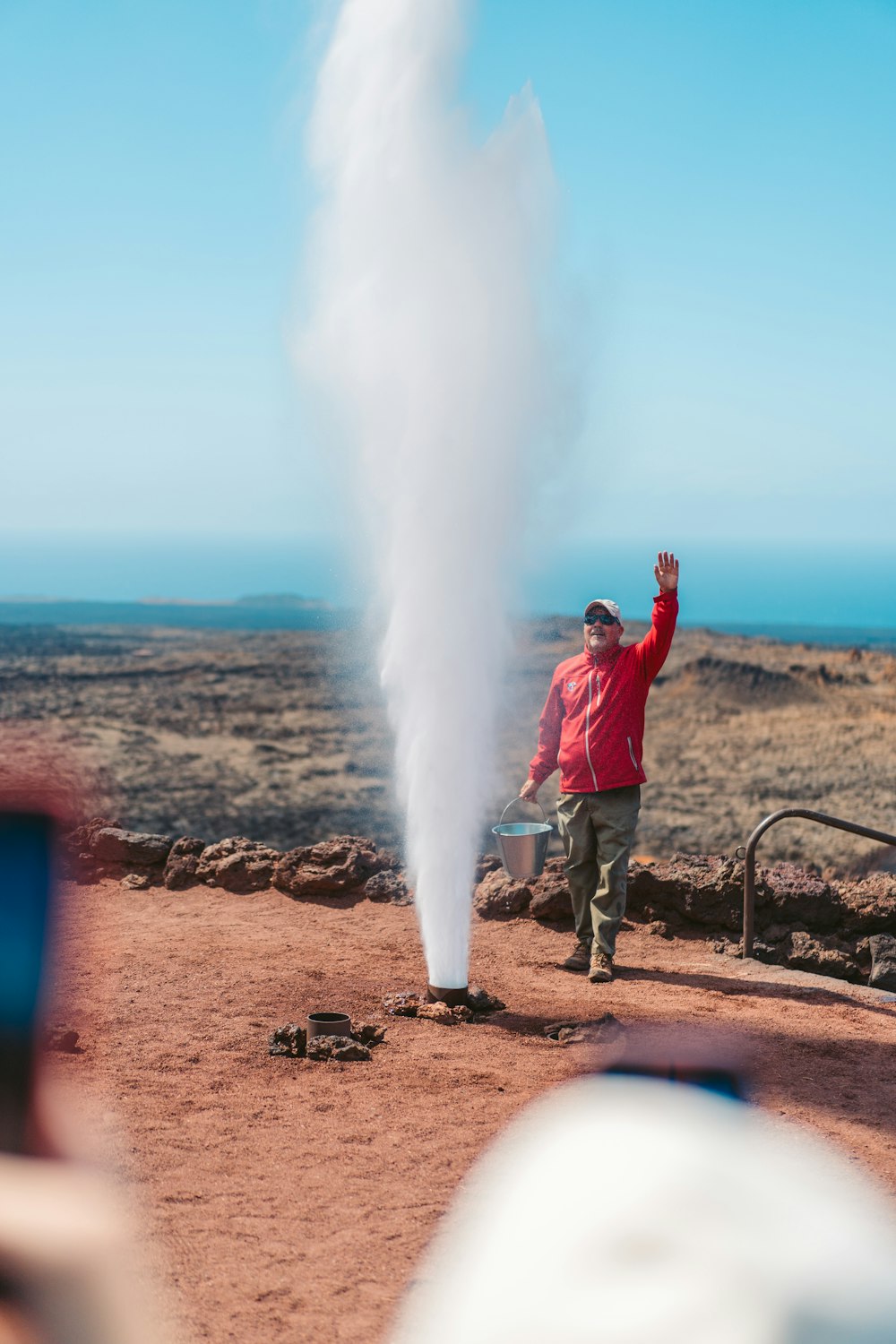 a man in a red jacket standing next to a plume of smoke