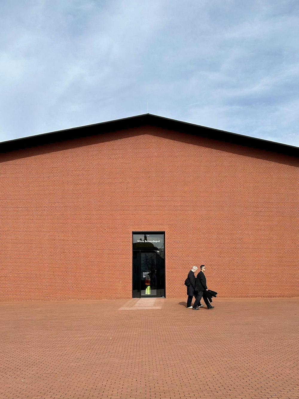 two people walking out of a brick building