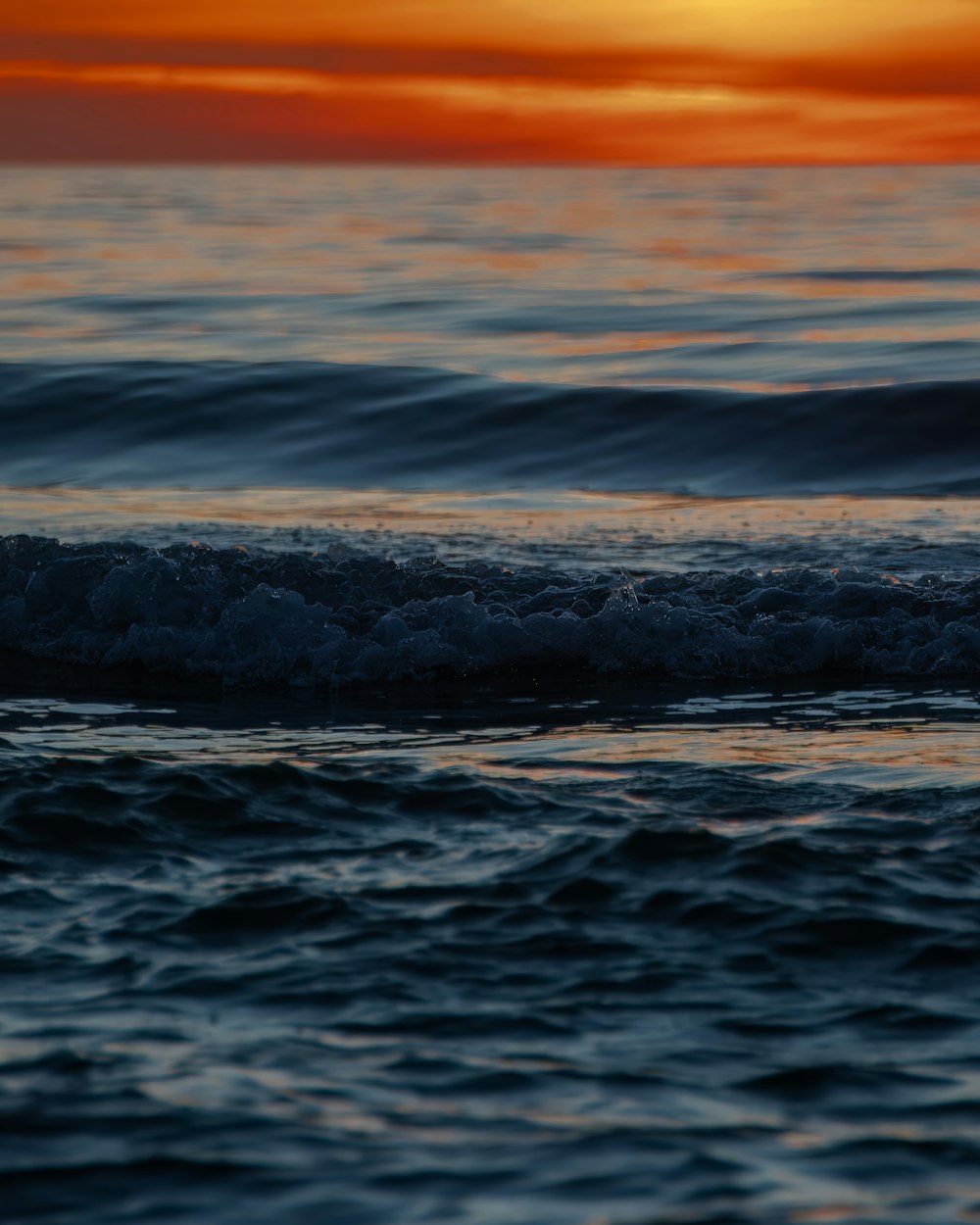 the sun is setting over the ocean waves