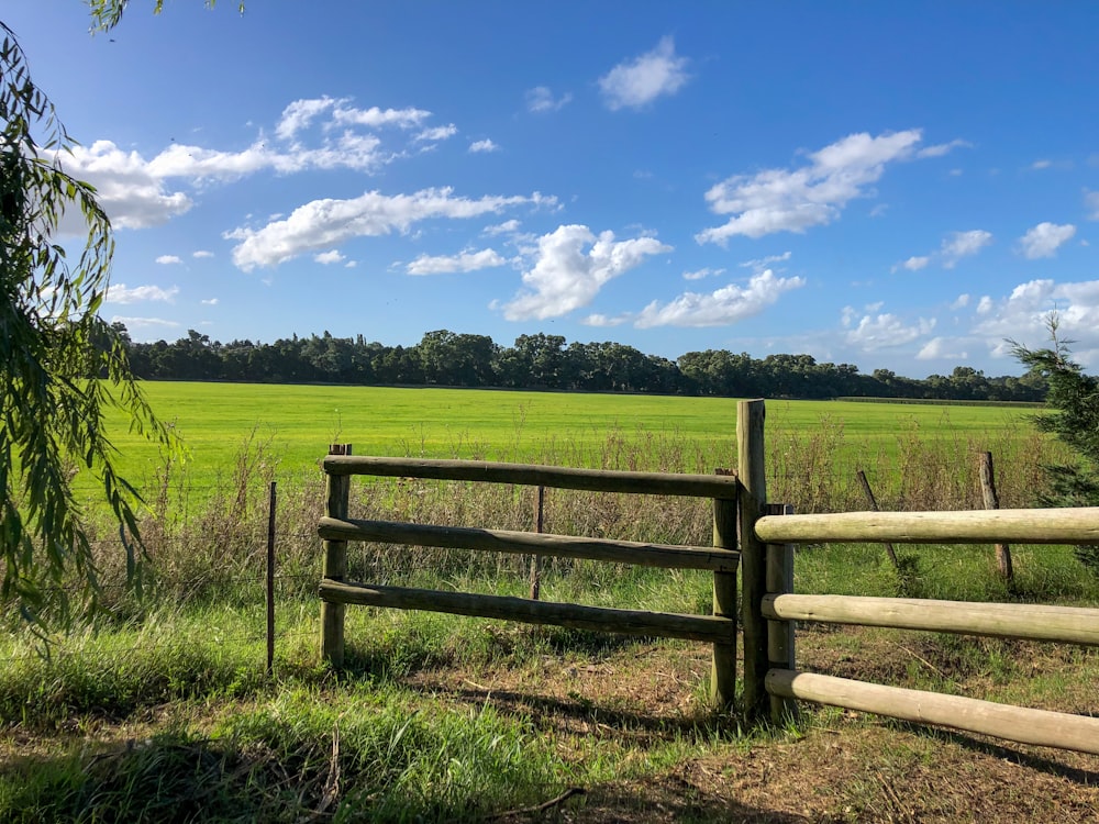 a wooden fence in front of a green field