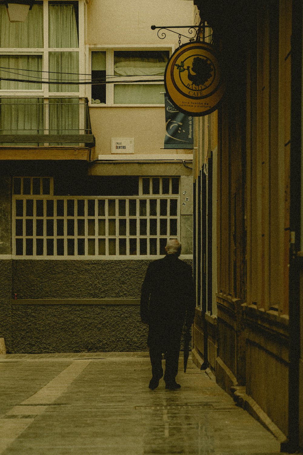 a man walking down a sidewalk next to a tall building