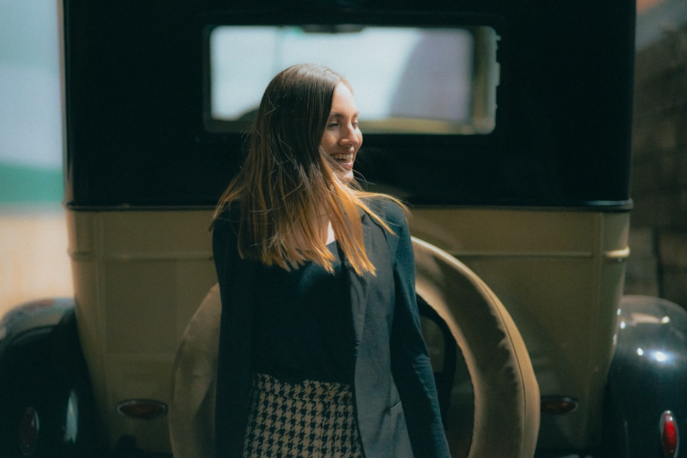 a woman standing in front of an old car