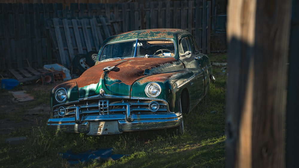 an old rusty car sitting in the grass
