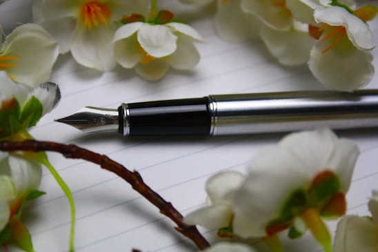 a pen sitting on top of a piece of paper next to flowers