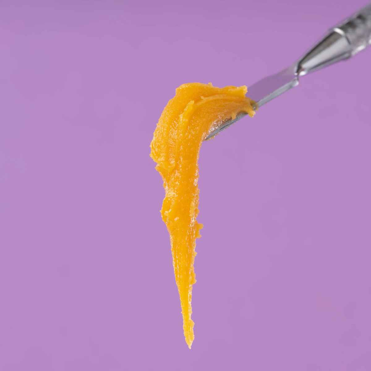 Golden cannabis concentrate smeared on a stainless steel dab tool