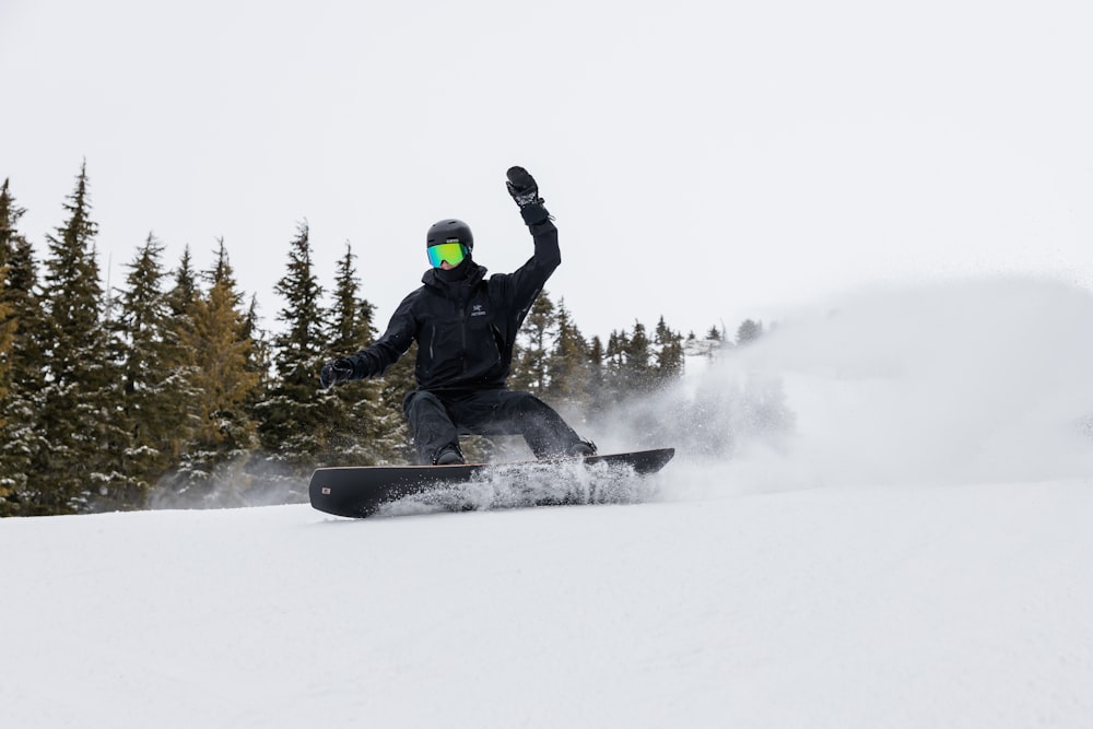 a man riding a snowboard down a snow covered slope