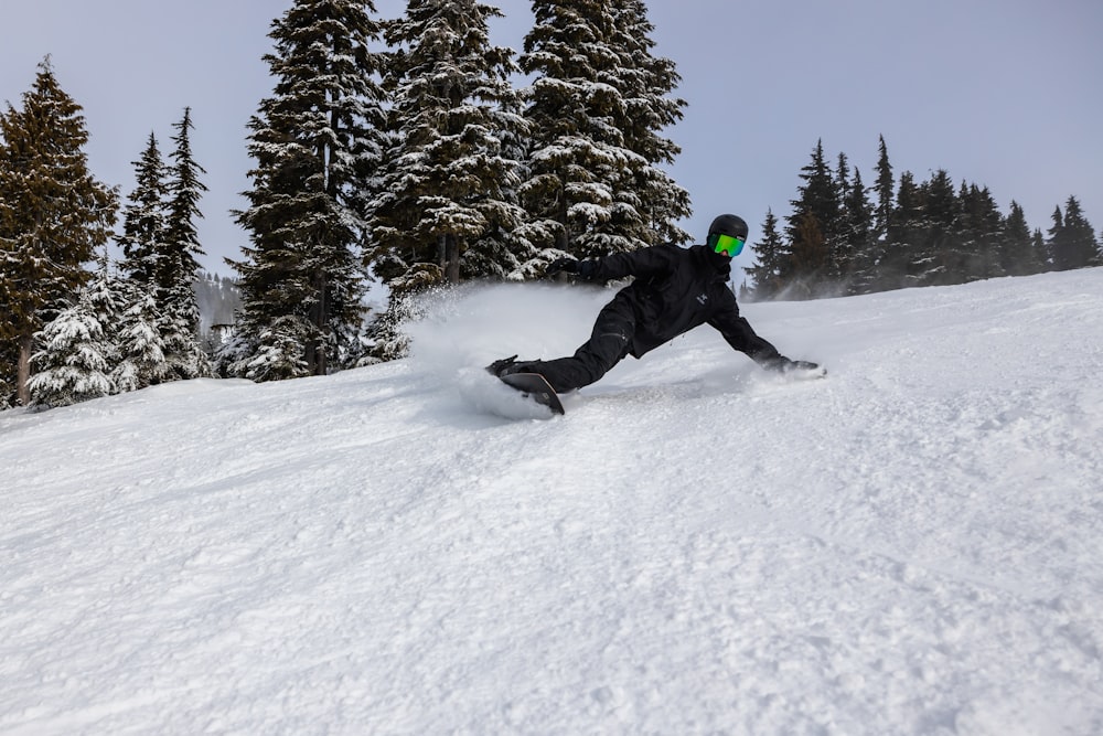 a man riding a snowboard down a snow covered slope