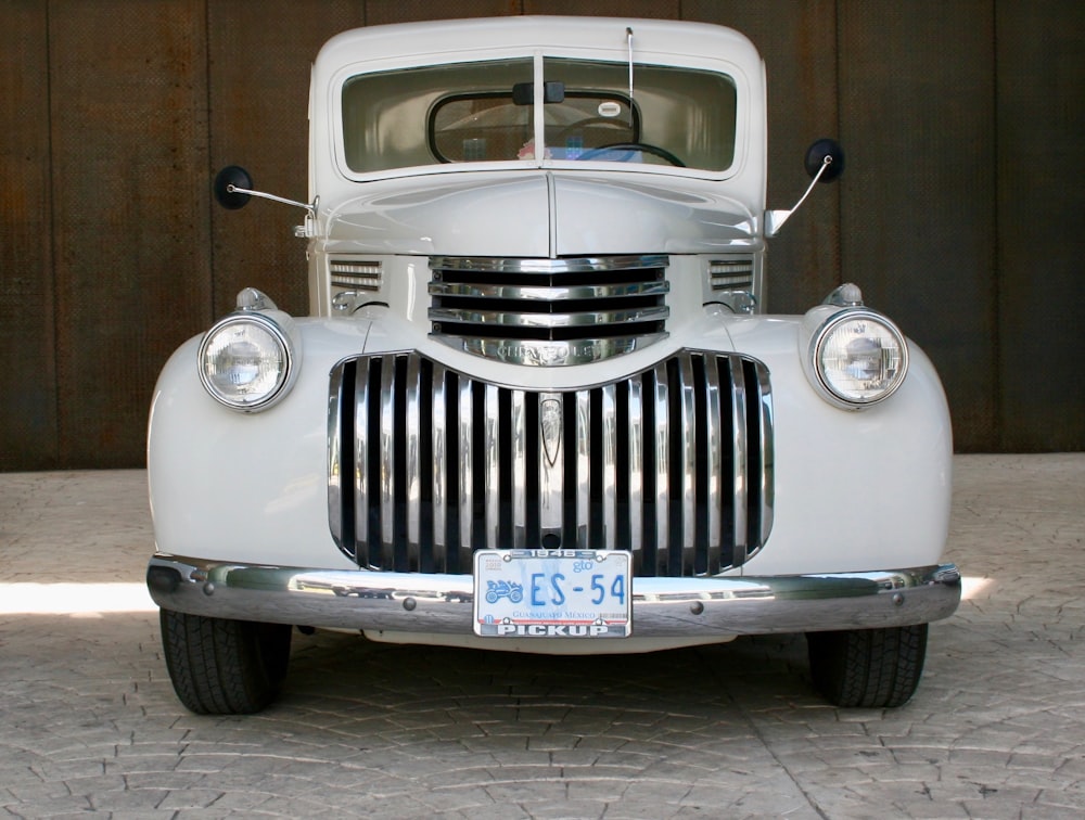 an old white truck parked in front of a garage door