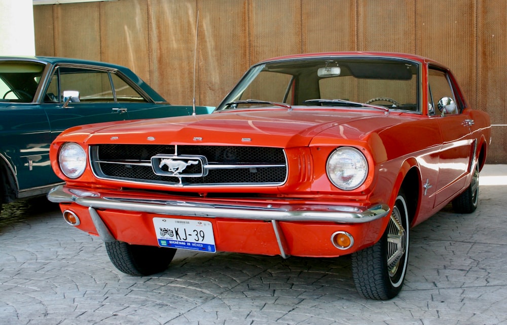 a red mustang parked next to a green mustang