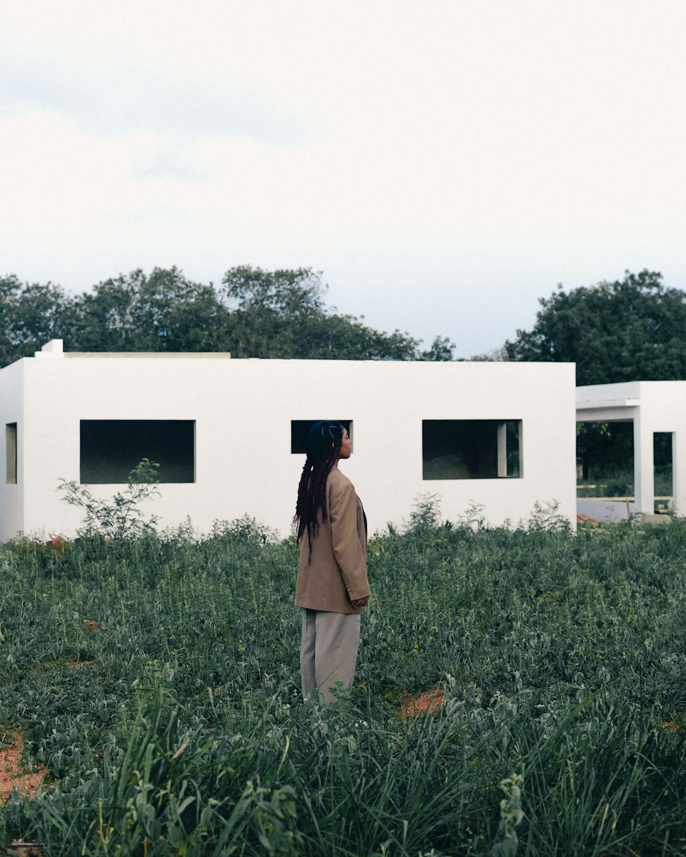 a person standing in a field with a house in the background