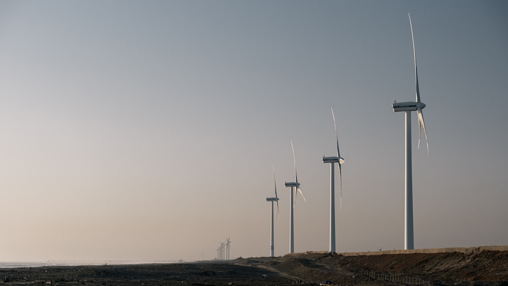 a row of wind turbines next to a dirt field