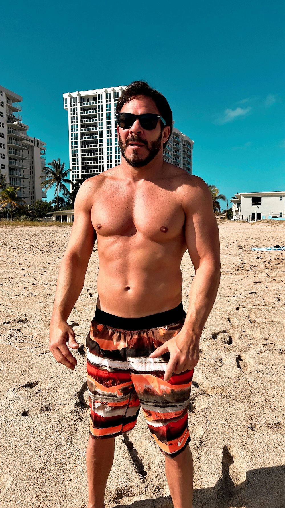 a shirtless man standing on a sandy beach
