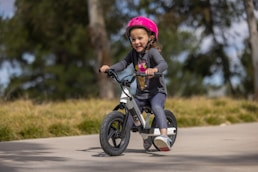 a little girl riding a bike with a helmet on