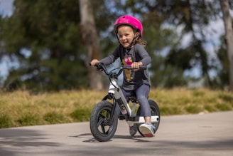 a little girl riding a bike with a helmet on