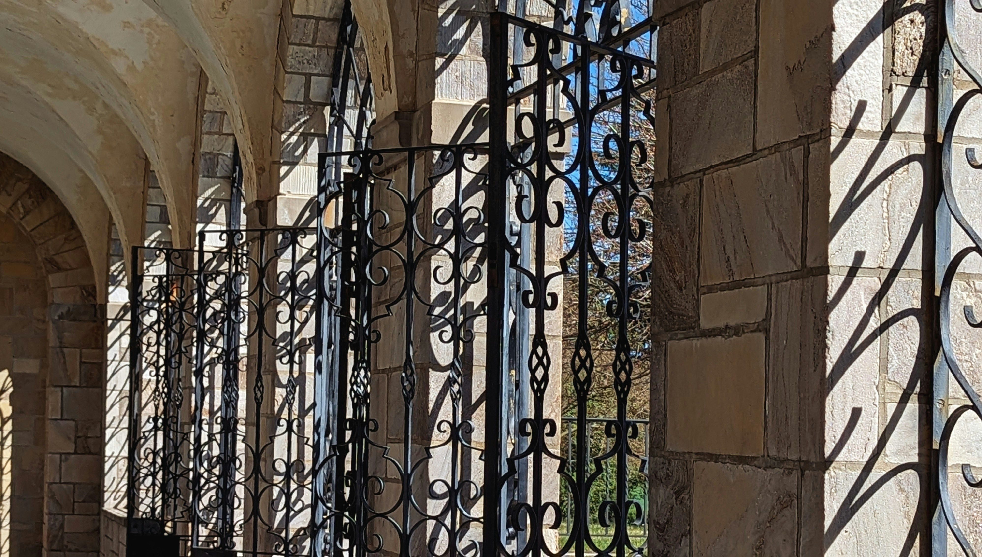 Luxury residential entrance with custom aluminum gate, dramatic architectural lighting, deep charcoal shadows