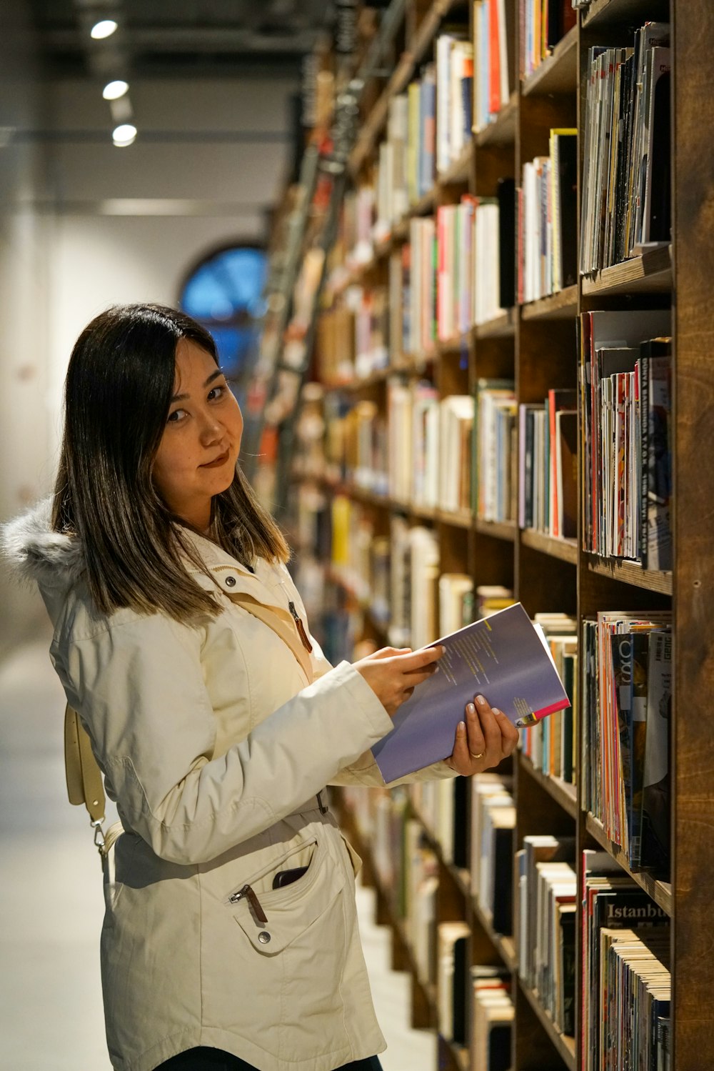 uma mulher olhando para um livro em uma biblioteca