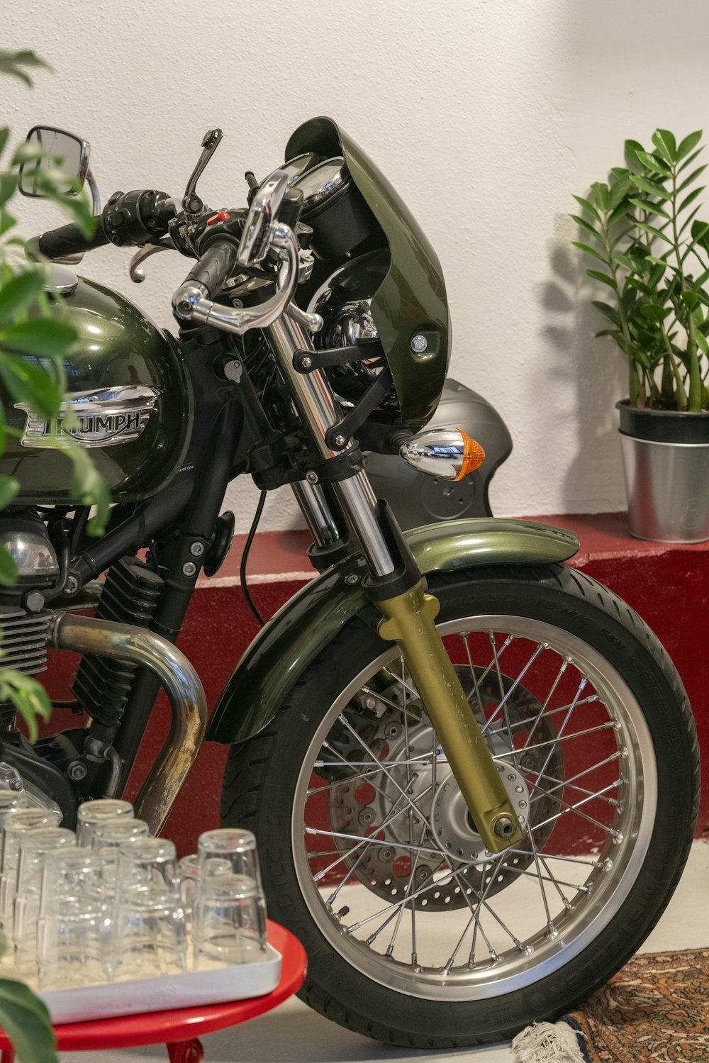 a green motorcycle parked next to a potted plant