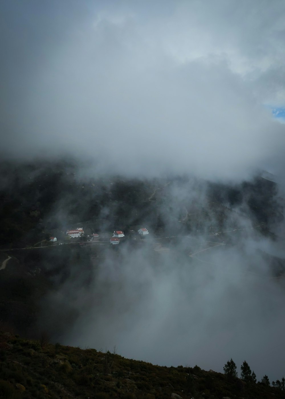 a foggy mountain with houses in the distance