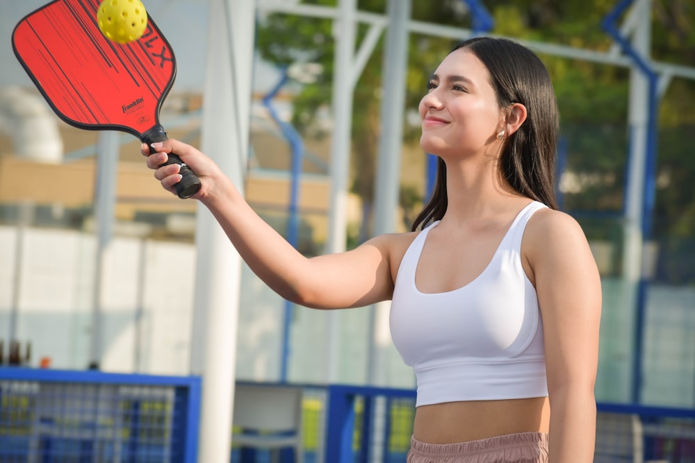 a woman holding a tennis racket and ball