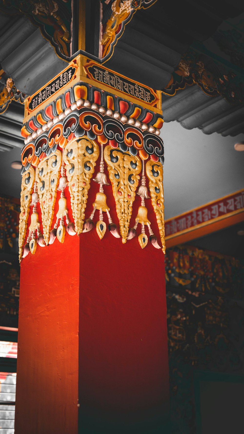 a red pillar with ornate decorations on top of it