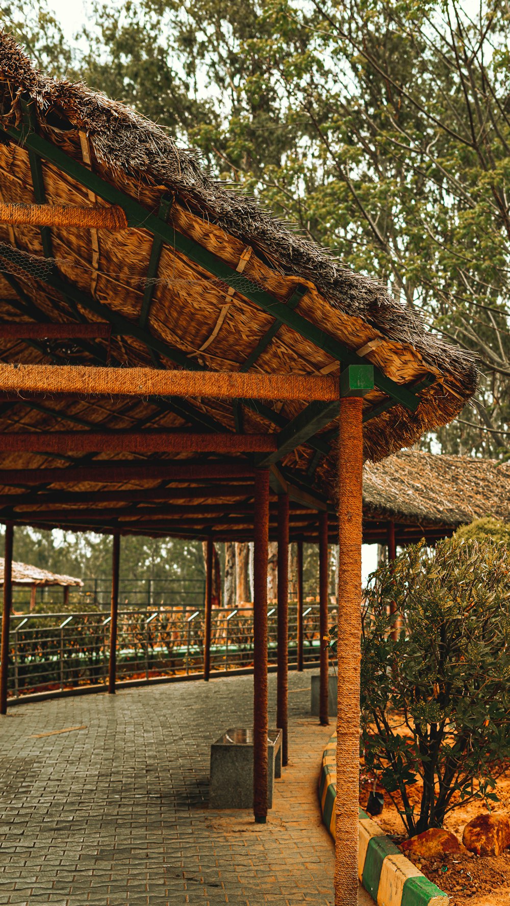 a bench under a thatched roof in a park