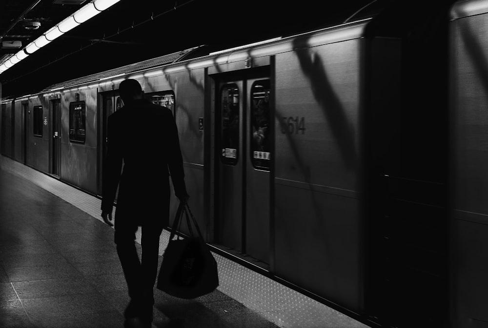 a man with a bag walks down a subway platform