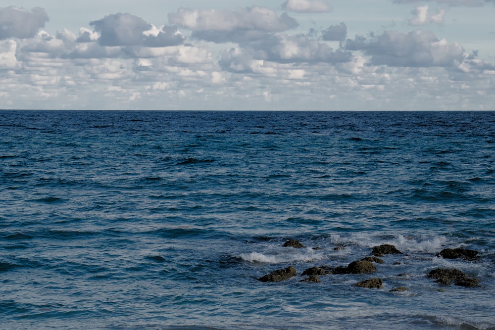 a large body of water with rocks in the foreground