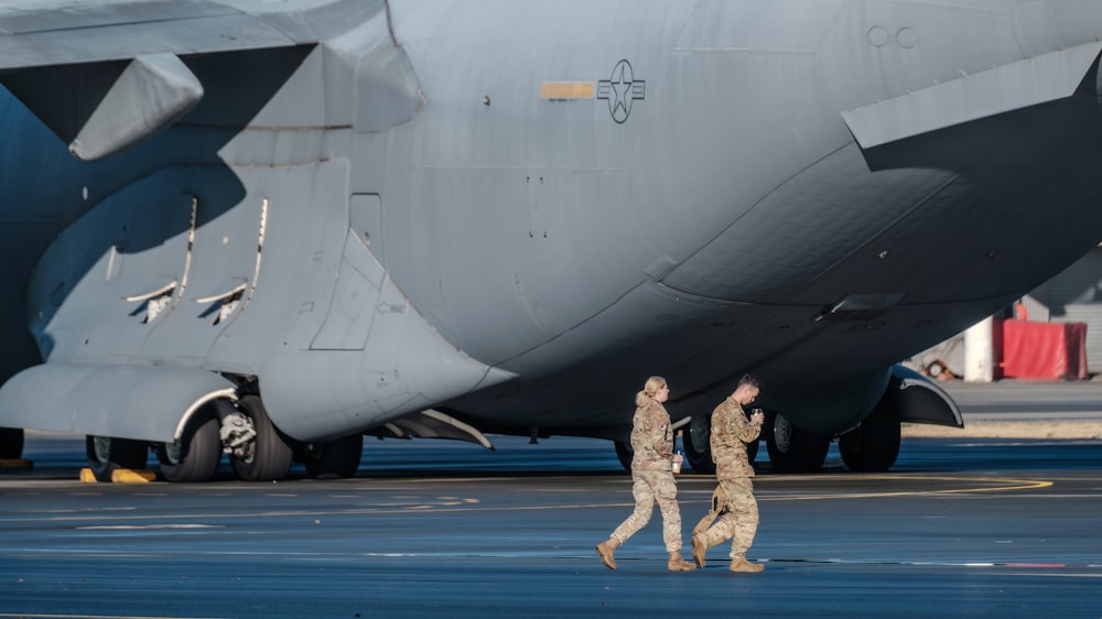 a couple of men walking next to a large airplane