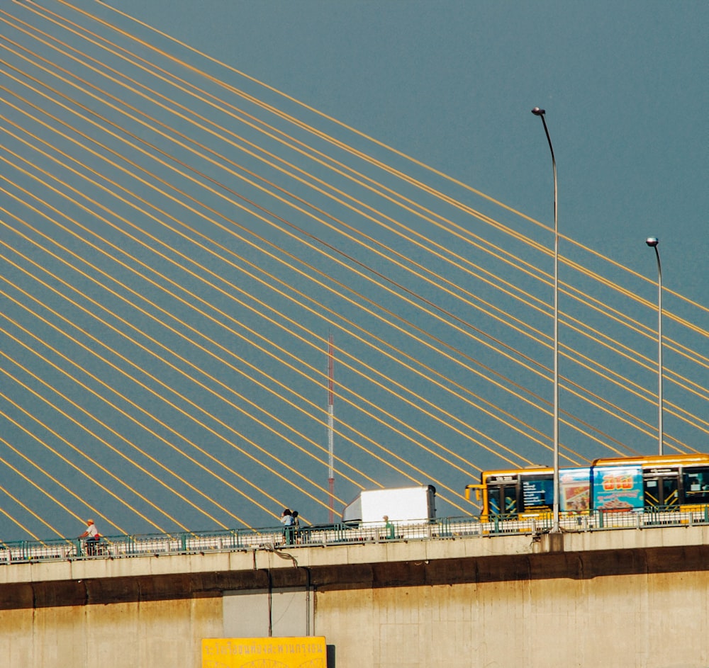 a yellow and white bus driving over a bridge