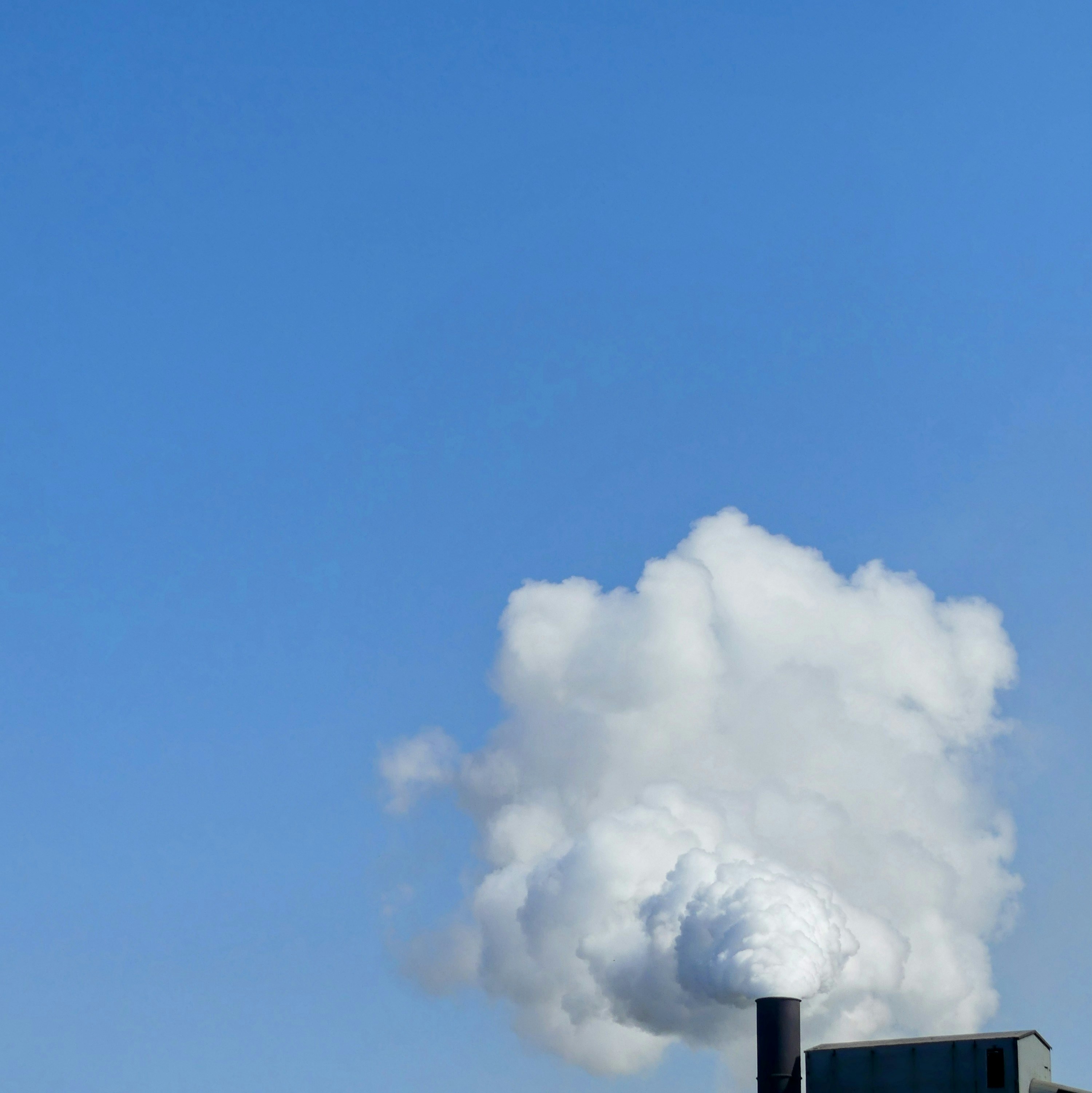 A factory with smoke coming out of it's stacks photo – Free Blue sky ...